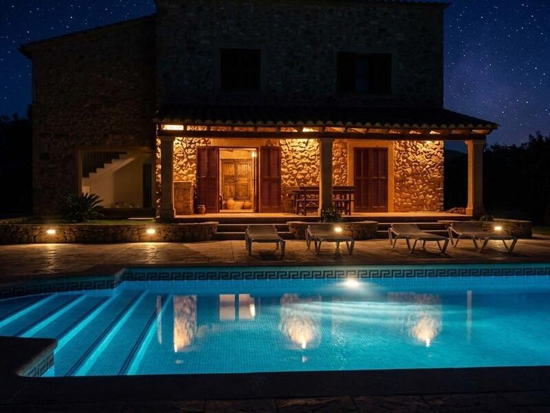 Piscina iluminada de noche frente a la casa