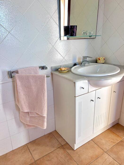 Lavabo con mueble blanco y suelo de barro