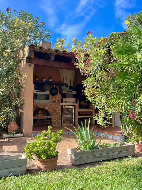 Cocina exterior con horno y barbacoa entre adelfas