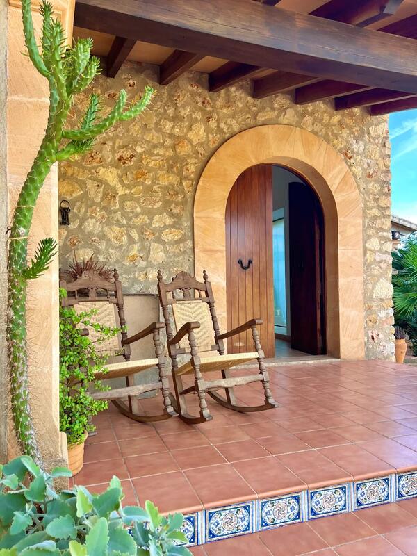Puerta de madera bajo arco de piedra con mecedoras