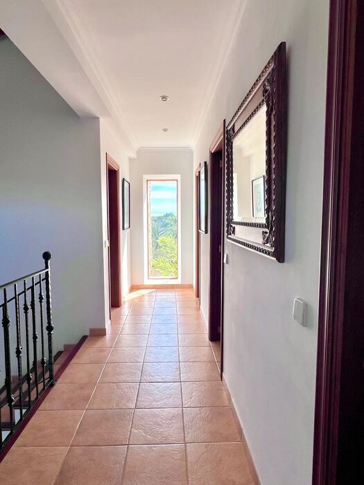 Pasillo de la planta superior con barandilla de forja y ventana al jardín