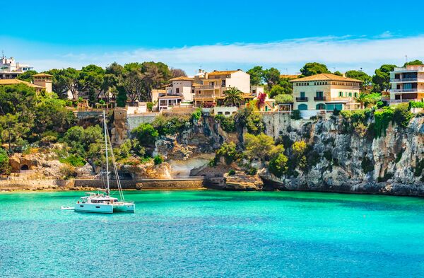 Puerto de Porto Cristo con aguas turquesa y casas sobre el acantilado